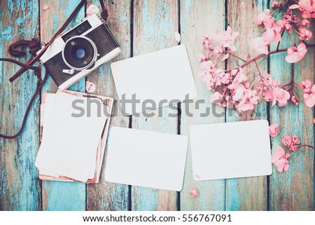 Retro camera and empty old instant paper photo album on wood table with flowers border design - concept of remembrance and nostalgia in spring. vintage style