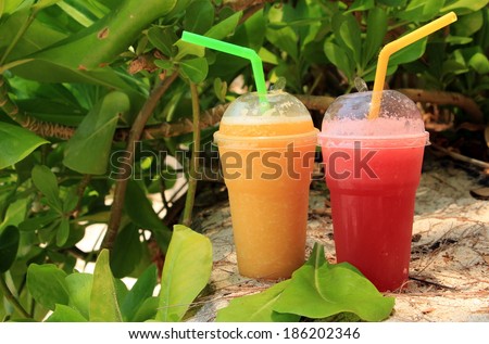 Different fresh juices in plastic cups. Mango juice, watermelon juice.