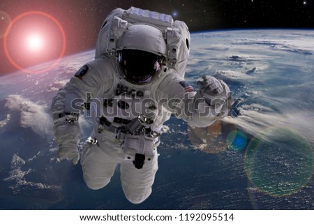 astronaut flying in outer space near planet earth doing some work near space ship