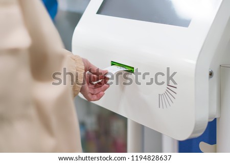 close up customer hand pull a ticket number from dispenser machine to wait in queue in post office