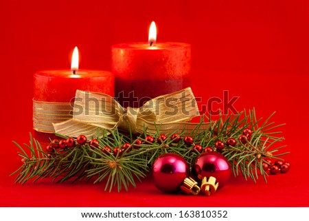 Two red candles with xmas tree and purple toys on red background