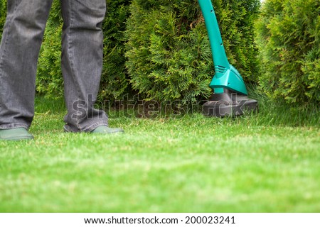 man mowing lawn with grass trimmer