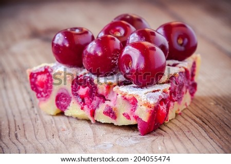 slice of Clafoutis cherry pie on a rustic wooden background