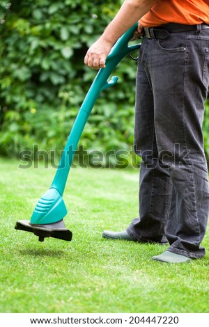 man mowing lawn with electric grass trimmer
