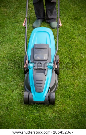 man with an electric mower on green grass