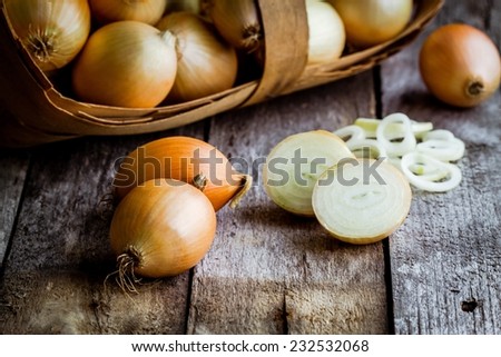 Fresh organic onions in a basket on a wooden background
