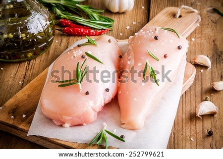 raw chicken fillet with garlic, pepper and rosemary on a wooden background