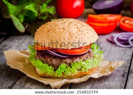 homemade hamburger close up with fresh green lettuce tomato and red onion on rustic background homemade hamburger close up with fresh green lettuce tomato and red onion on rustic background