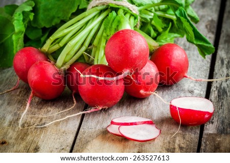 bundle of  bright fresh organic radishes with slices on wooden rustic table