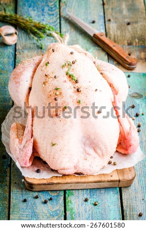 organic raw farm whole chicken with thyme and peppers on a rustic table