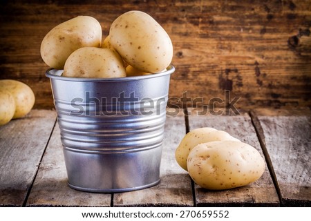 Fresh organic raw potatoes in a bucket on a wooden rustic table