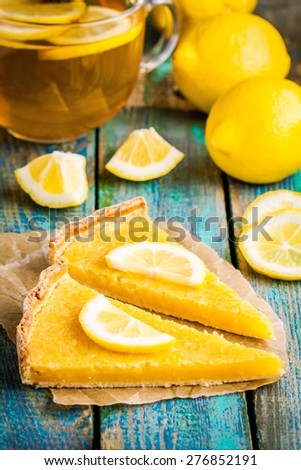 two pieces of lemon tart with slice of lemons on rustic blue table
