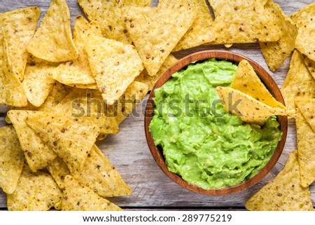 homemade guacamole with corn chips top view on rustic wooden table