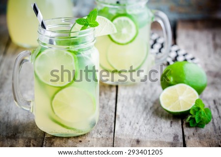 homemade lemonade with lime, mint in a mason jar on a wooden rustic table