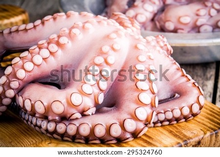 whole fresh raw octopus  on cutting board closeup on rustic wooden table