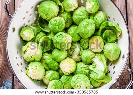 Fresh organic Brussels sprouts in a colander on a wooden table