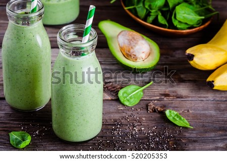 healthy green smoothie with banana, spinach, avocado  and chia seeds in a glass bottles on a rustic background