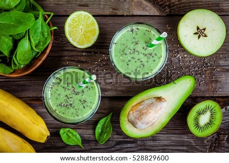 healthy green smoothie with banana, spinach, avocado and chia seeds in glass jars on a rustic background