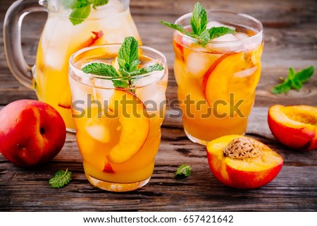 Summer cold drinks: homemade peach sangria with ice cubes, and mint in glass on wooden background