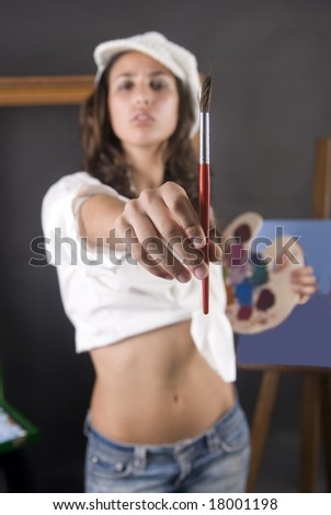 young woman painting a picture with brush in first plane
