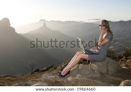 woman working with laptop in the mountain and talking by phone