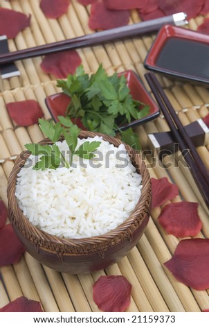 bowl of rice with oriental sticks over bamboo and roses and soja sauce