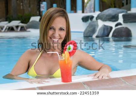beautiful woman with cocktail in a swimming pool