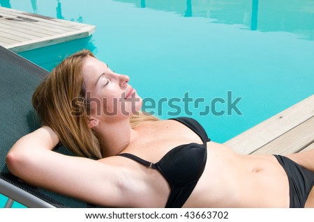 woman in holidays having a sun bath near a swimming pool