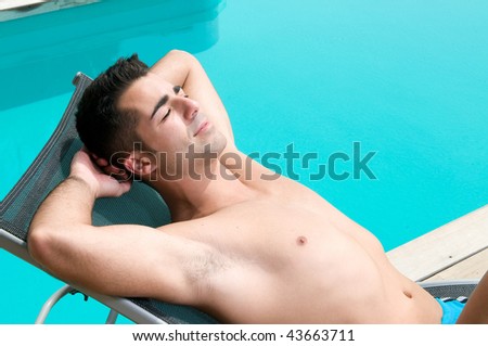 man in holidays having a sun bath near a swimming pool