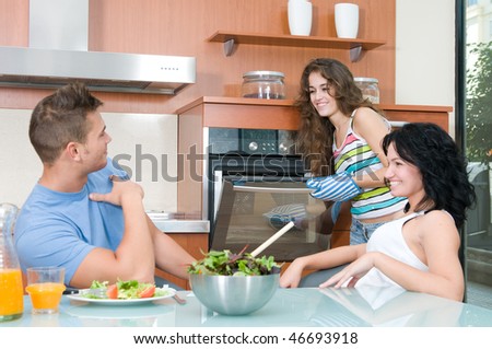 man and woman eating salad and woman at the oven