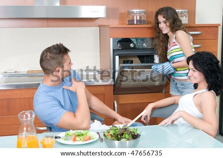 man and woman eating salad and woman at the oven