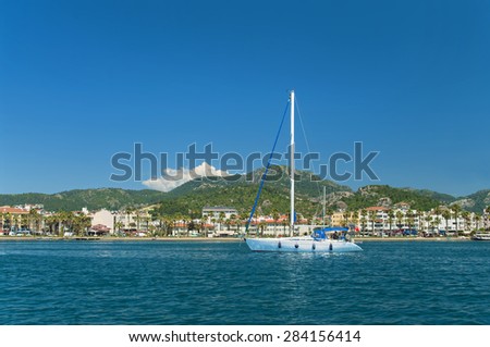 white yacht near city beach and hotels with mountains at back, Marmaris, Turkey