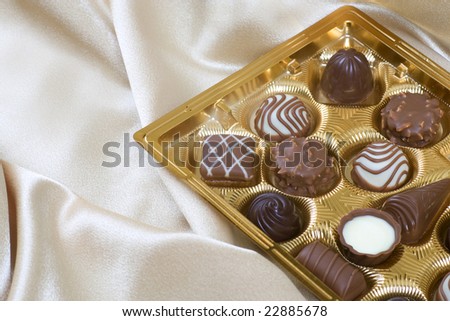 Box of chocolates sitting in cream silk