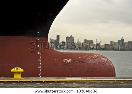 bow of large ship with draft scale numbering , large african city in the background (durban, south africa)