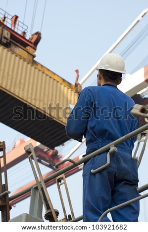 Harbor worker - watching the loading operation . Real situation photo.