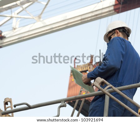 Harbor worker - watching the loading operation . Real situation photo.