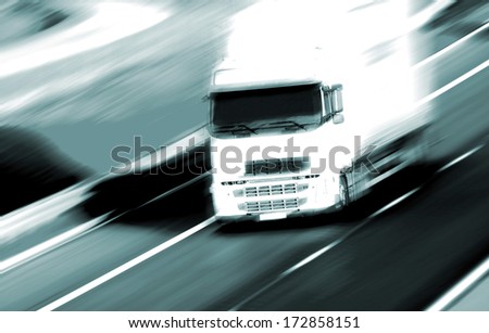 Red truck on blurry asphalt road over blue cloudy sky background