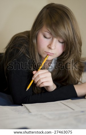 natural pretty girl reading book on a bed with a pencil in her mouth