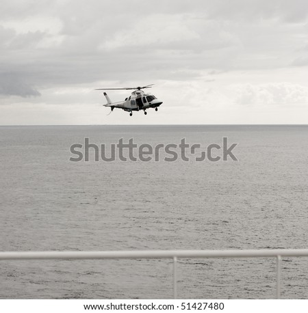 Flying helicopter on sky and sea background