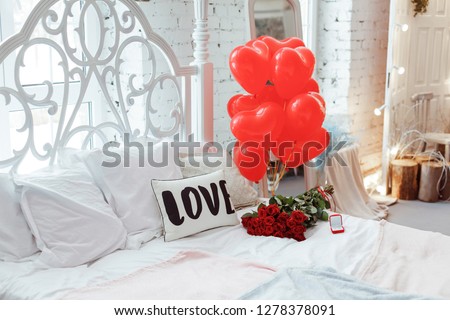 Celebrating Saint Valentine\'s Day with red roses on bed and air balloons in shape of heart on the bed. Gift for girlfriend on Valentine`s day,Women`s day.
