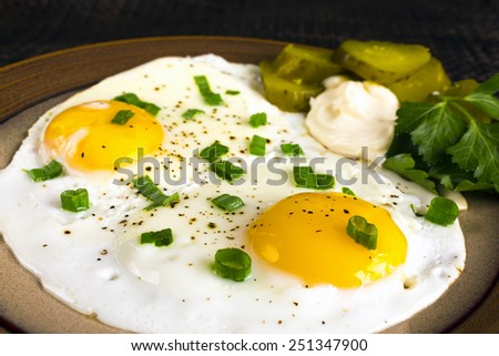 Fried eggs with spices, pickles, leeks and parsley. Selective focus