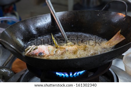 frying bass fish in frying pan with hot oil