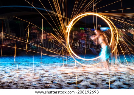 man doing fire show on beach at night