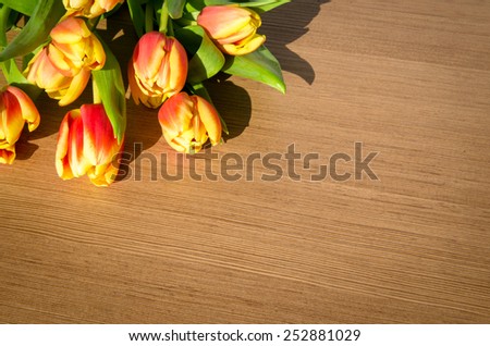 orange yellow tulips bunch over wooden background