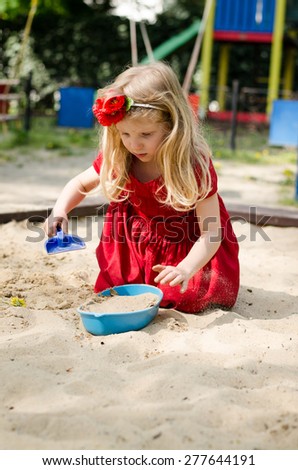 beautiful blond girl playing in sandpit