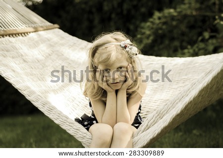 beautiful blond girl sitting in white hammock