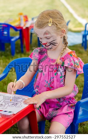girl with face-painting of cat drawing with paintbrush