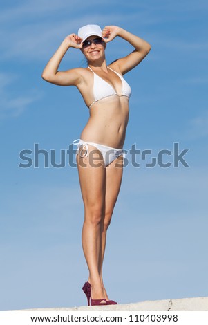 Girl at the sea. Young woman in white bikini posing on background of sky