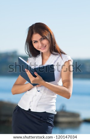 Attractive long haired brunette on open air. Young business woman reads on open air