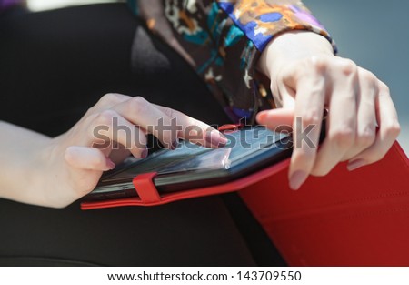 Girl uses touchpad outdoors. Woman's hands on tablet-pc on open air